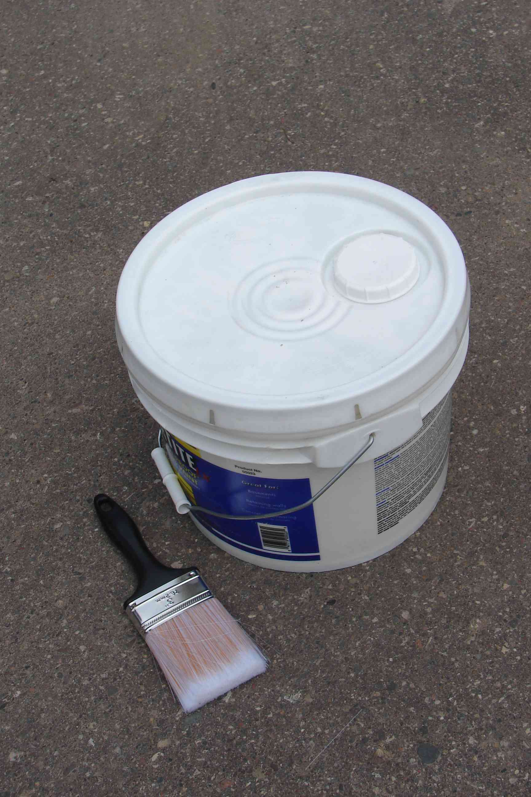 Plastic pail of paint and a paintbrush