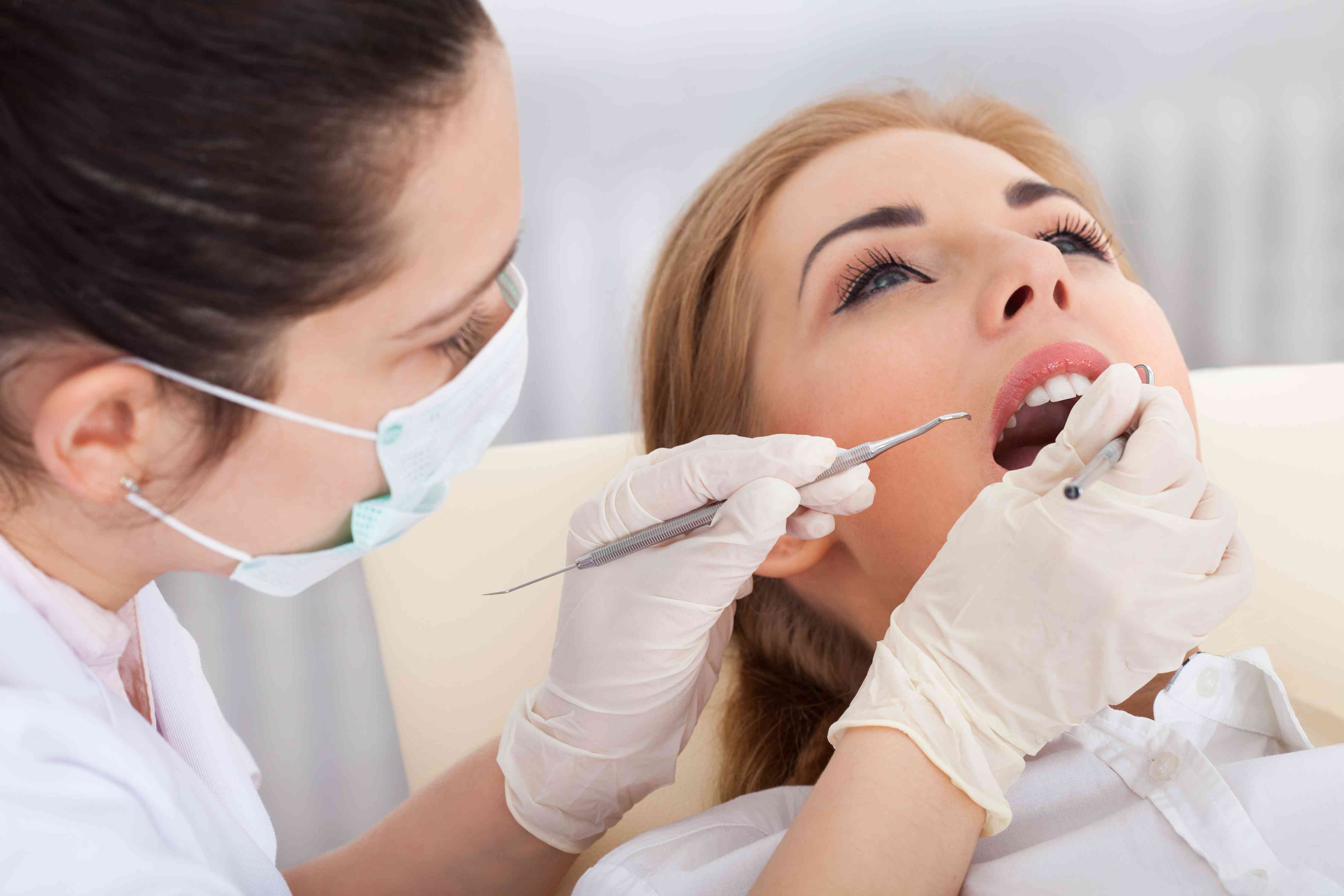 a dentist methodically checking the teeth of her patient