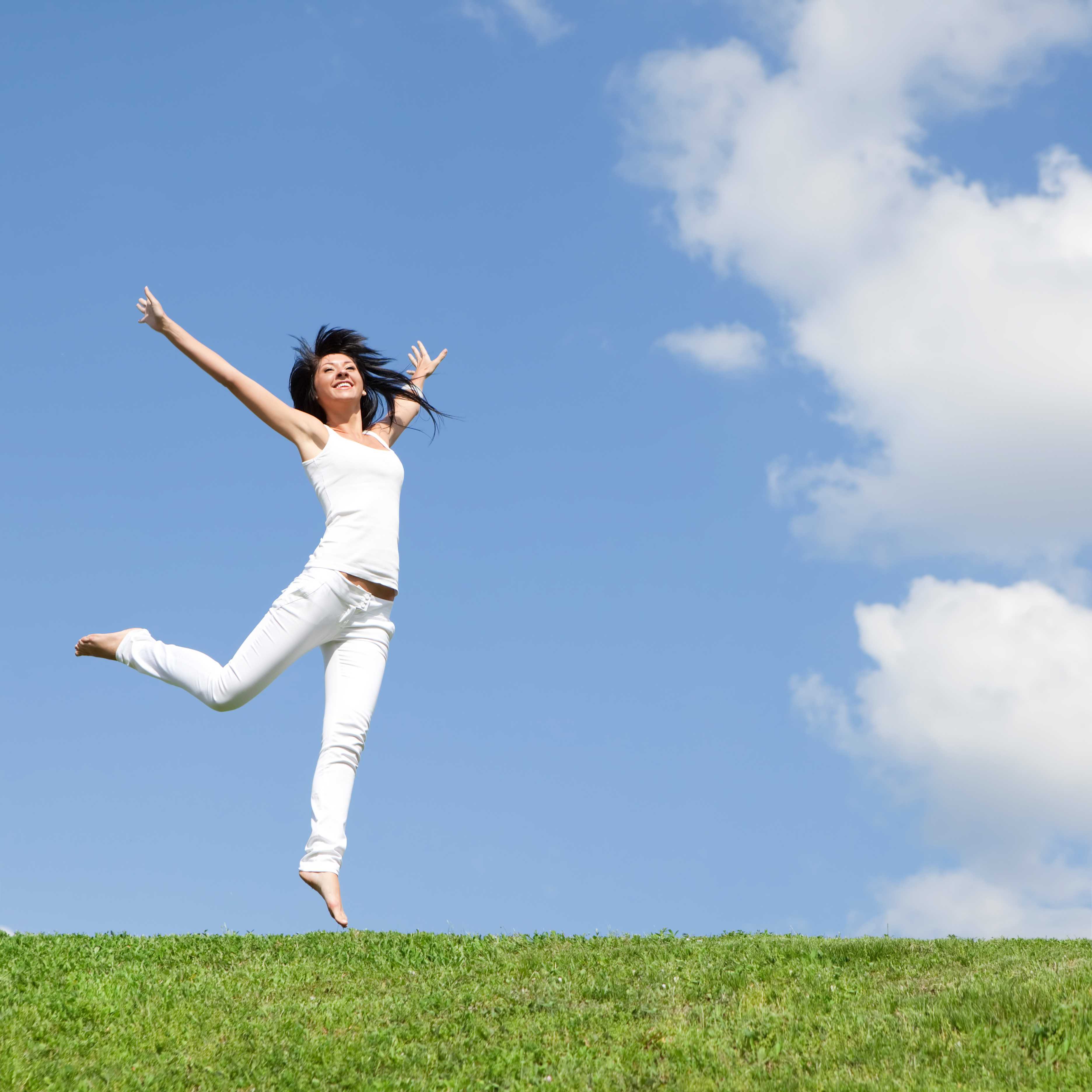 Woman leaping in a field of grass