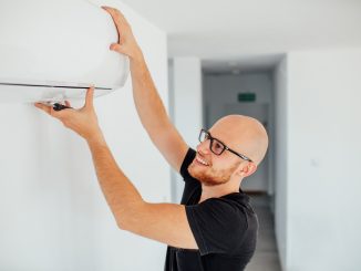 man adjusting AC to change room temp