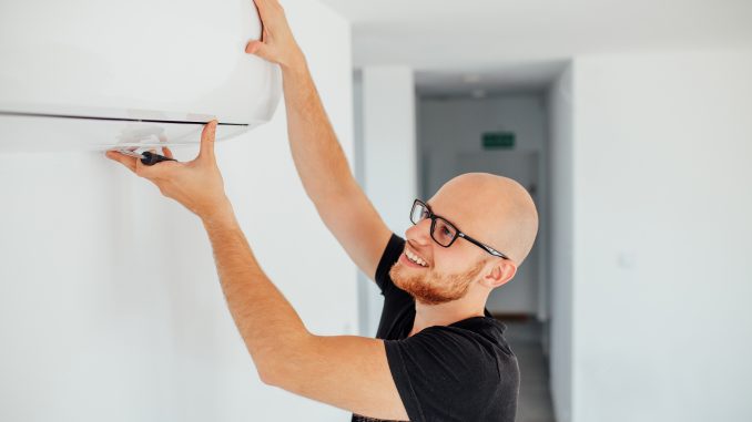 man adjusting AC to change room temp