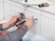 Plumber hands fixing water tap with spanner