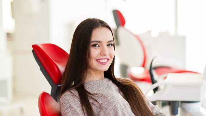 a woman with a bright smile sitting on a dental chair