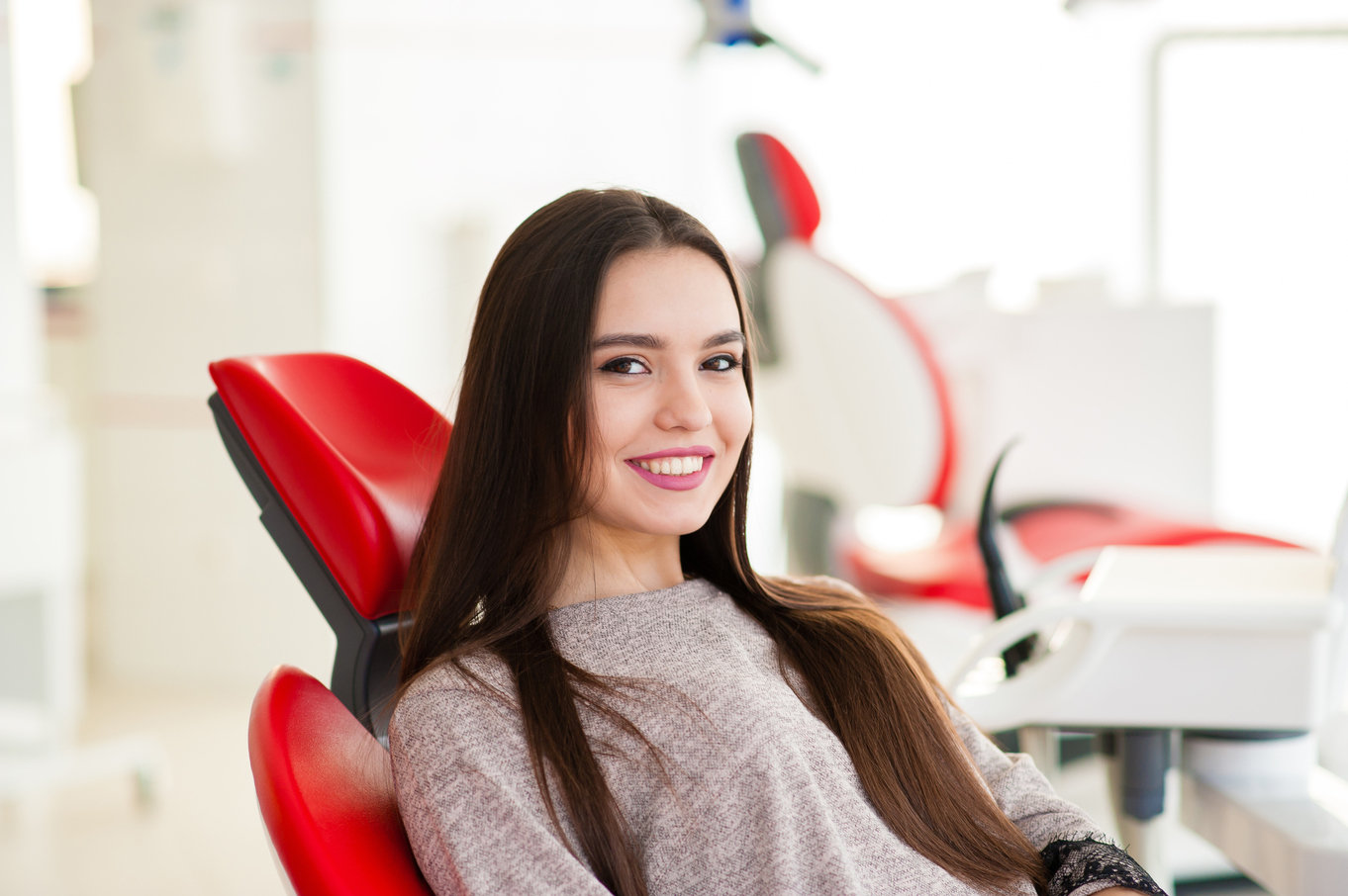 a woman with a bright smile sitting on a dental chair
