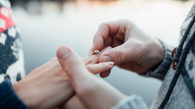 Man putting ring on woman hand