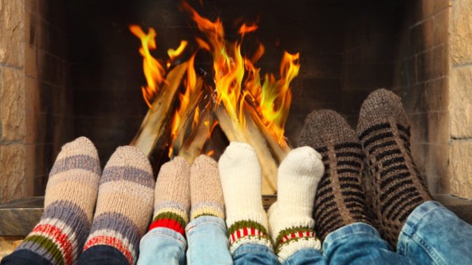 Feets of a family wearing woolen socks warming near the fireplace