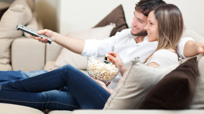 couple watching tv while eating popcorn