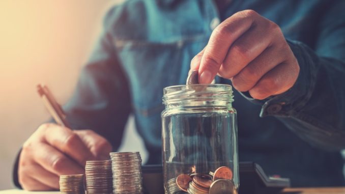 Man saving money putting coins in jar