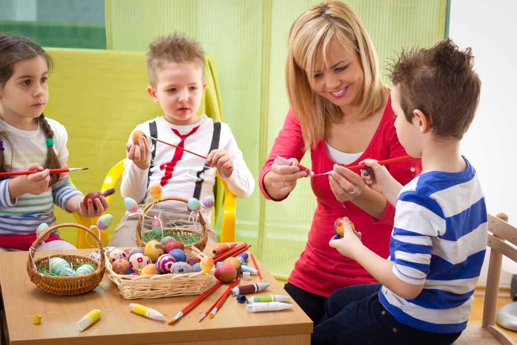 Woman painting eggs with kids