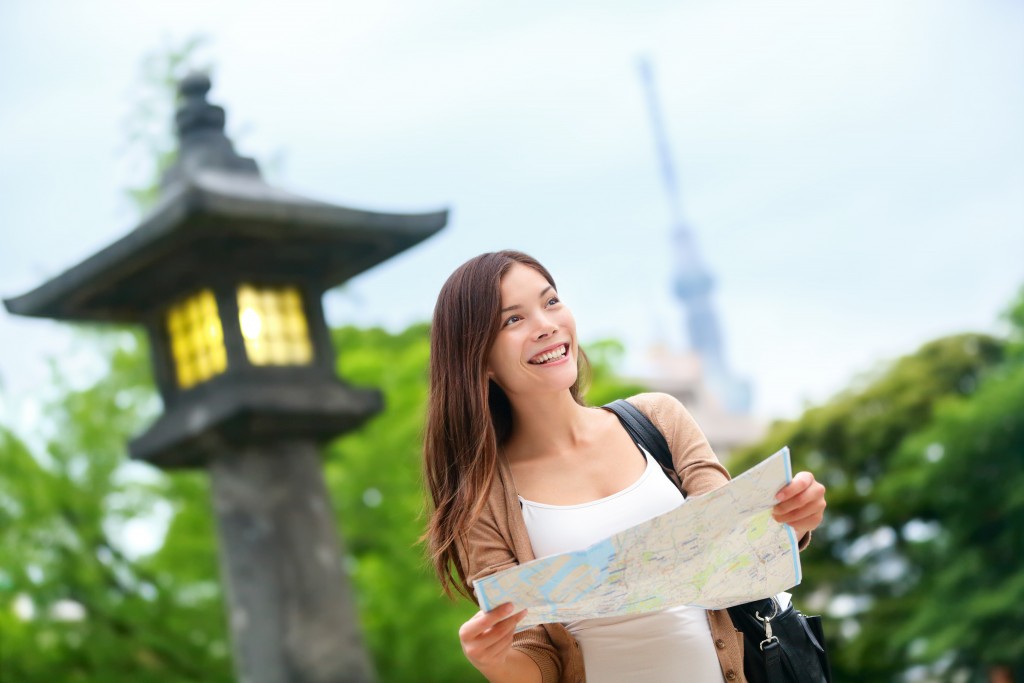 sian tourist woman with map searching for directions with the Tokyo Skytree tower in the background