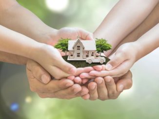 hands holding a small house model