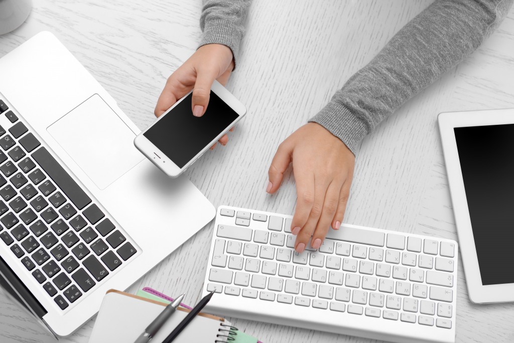 woman using smartphone and laptop