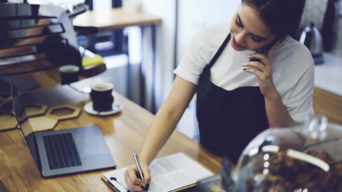 Woman writing on form while talking on the phone