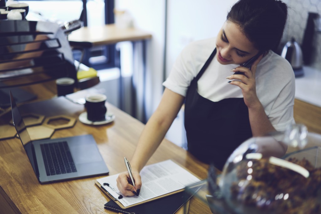 Woman writing on form while talking on the phone