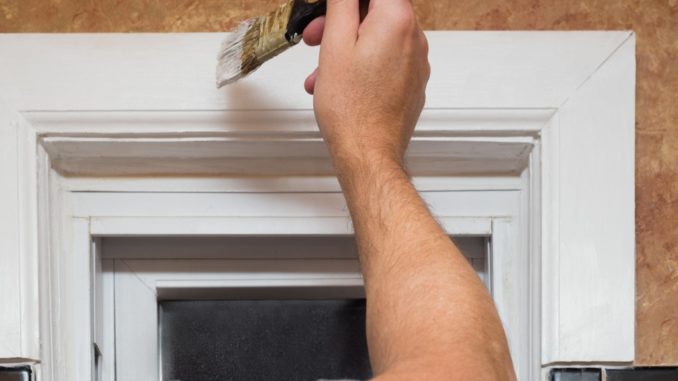 person painting the door frame white