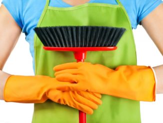 Woman wearing apron and gloves while holding a broom